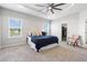 This primary bedroom features a tray ceiling with fan, plush carpet and large windows at 35519 Bellington Blvd, Zephyrhills, FL 33541