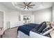 The primary bedroom features a tray ceiling with fan, plush carpet and view to the kitchen at 35519 Bellington Blvd, Zephyrhills, FL 33541