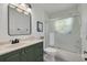 Bathroom showcasing modern green vanity, a tub with a glass door, and a rectangular mirror at 4766 Royal Palm Ne Cir, St Petersburg, FL 33703