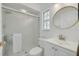 Well-lit bathroom featuring a frosted glass shower door, modern sink, and round mirror at 4766 Royal Palm Ne Cir, St Petersburg, FL 33703