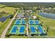 Aerial view of tennis courts, lake, trees, and landscaped grounds at 4946 Mill Pond Rd # 3180, Wesley Chapel, FL 33543