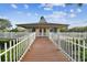 Clubhouse at the end of a wooden walkway features a peaked roof and white fence at 4946 Mill Pond Rd # 3180, Wesley Chapel, FL 33543