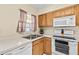 Bright kitchen with stainless steel sink, white appliances, and wooden cabinetry at 732 Kensington Lake Cir, Brandon, FL 33511