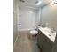 Bright bathroom featuring a tub-shower combination, toilet, and vanity with a gray cabinet at 7506 Presley Pl # 107, Tampa, FL 33617