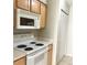 Kitchen featuring white appliances including stove and microwave, along with natural wood cabinets at 7506 Presley Pl # 107, Tampa, FL 33617