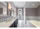 Primary bathroom featuring double sinks, soaking tub, marble tiling and shower at 755 Bay Esplanade, Clearwater Beach, FL 33767