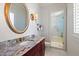 Bathroom featuring a vanity with a round mirror, granite countertop and a glass-enclosed shower at 755 Bay Esplanade, Clearwater Beach, FL 33767