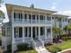 Elegant two-story home featuring a covered porch with stately columns and manicured landscaping at 755 Bay Esplanade, Clearwater Beach, FL 33767