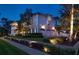 Exterior view of a home with three garage doors and a manicured lawn illuminated at dusk at 755 Bay Esplanade, Clearwater Beach, FL 33767
