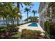 Beautiful waterfront property featuring a swimming pool, mature trees, and lush landscaping, perfect for outdoor relaxation at 755 Bay Esplanade, Clearwater Beach, FL 33767