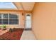 Inviting front entrance featuring a white door, a sidelight window, and lush mulch landscaping at 8531 Woodcrest Dr, Port Richey, FL 34668