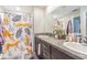 Bathroom with double sinks, decorative shower curtain and a stylishly patterned accent rug at 9411 Lemon Drop Loop, Sun City Center, FL 33573