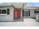 Home exterior with red front door, black shutters, and neutral gray paint at 10602 Camelia Dr, Port Richey, FL 34668