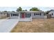 Charming home featuring fresh gray paint, red doors, and manicured landscaping at 10602 Camelia Dr, Port Richey, FL 34668