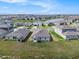Aerial view of the gray home surrounded by well-manicured lawn in a suburban community with a small pond at 11257 Linden Depot Rd, San Antonio, FL 33576