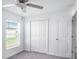 A bright bedroom with gray carpet, ceiling fan, closet, and a window at 11257 Linden Depot Rd, San Antonio, FL 33576