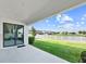 A covered back patio overlooking a green lawn and a picturesque pond with a white picket fence at 13130 Monach Isles Dr, Riverview, FL 33579