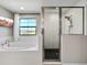 Modern bathroom with soaking tub, walk-in shower, and a large window that provides a view of the neighborhood at 13130 Monach Isles Dr, Riverview, FL 33579