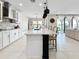 Modern kitchen features white cabinets, a dark center island, stylish pendant lighting, and an open-concept design at 13130 Monach Isles Dr, Riverview, FL 33579
