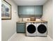Well-organized laundry room with modern washer and dryer, ample counter space, and stylish blue cabinets at 13130 Monach Isles Dr, Riverview, FL 33579