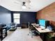 Spacious home office with exposed brick, desk setup, and dark blue walls at 13130 Monach Isles Dr, Riverview, FL 33579