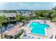 Aerial view of a sparkling community pool surrounded by lounge chairs, lush landscaping, and waterfront views at 1316 Pasadena S Ave # 303, South Pasadena, FL 33707