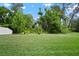Lush green backyard with mature trees and manicured lawn and partial view of a white fence at 13311 Orca Sound Dr, Riverview, FL 33579