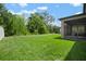 Large backyard featuring lush green grass, mature trees, and a screened-in patio at 13311 Orca Sound Dr, Riverview, FL 33579