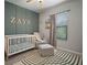 Bedroom featuring a white crib, comfortable glider, and decorative 'Zayn' wall art at 13311 Orca Sound Dr, Riverview, FL 33579