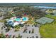 An aerial view features a community pool, clubhouse, parking lot, tennis and basketball courts surrounded by trees and green spaces at 13311 Orca Sound Dr, Riverview, FL 33579