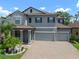 Charming two-story home featuring a three-car garage, brick paved driveway, and tropical landscaping at 13311 Orca Sound Dr, Riverview, FL 33579