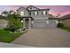 Charming two-story home featuring a three-car garage, brick paved driveway, and tropical landscaping at sunset at 13311 Orca Sound Dr, Riverview, FL 33579