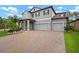 Charming two-story home featuring a three-car garage, brick paved driveway, and manicured landscaping at 13311 Orca Sound Dr, Riverview, FL 33579