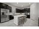 Modern kitchen with an island, sleek black cabinetry, stainless steel appliances, and stylish barstool seating at 13311 Orca Sound Dr, Riverview, FL 33579