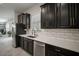 Well-equipped kitchen with a large sink, modern appliances, sleek black cabinetry, and stylish backsplash at 13311 Orca Sound Dr, Riverview, FL 33579