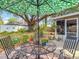 Private backyard with a metal outdoor dining set, patio, green umbrella, and mature trees at 1432 Windjammer Pl, Valrico, FL 33594