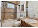 Well-lit bathroom featuring tiled walls, a shower-tub combo, a commode, and vanity at 1709 Sunset Dr, Tarpon Springs, FL 34689