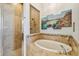 Well-lit main bathroom features travertine tile, a soaking tub, a shower, and decorative art at 1709 Sunset Dr, Tarpon Springs, FL 34689