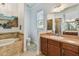 Well-lit main bathroom features travertine tile, a soaking tub, a shower, and a wooden vanity at 1709 Sunset Dr, Tarpon Springs, FL 34689
