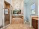 Well-lit main bathroom features travertine tile, a soaking tub, a shower, and a decorative chandelier at 1709 Sunset Dr, Tarpon Springs, FL 34689