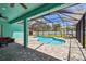 Screened in patio overlooks the sparkling pool and features a brick paver deck, landscaping, and fans at 1709 Sunset Dr, Tarpon Springs, FL 34689