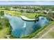 Scenic aerial view of a community with a golf course, pond and fountain surrounded by beautiful homes at 18514 Hidden Pines Way, Hudson, FL 34667