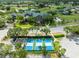 Aerial view of pickleball courts and the clubhouse with golf course in the background in a well-maintained neighborhood at 18514 Hidden Pines Way, Hudson, FL 34667