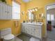 Bright yellow bathroom with double vanity, ample storage, and large mirror at 18514 Hidden Pines Way, Hudson, FL 34667