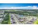 Aerial view captures a neighborhood next to a pond, showcasing homes equipped with solar panels under a clear, partly cloudy sky at 1876 Colding Dr, Ruskin, FL 33570