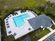 An aerial view of a community pool with a pool house, lounge chairs, and green landscaping at 1876 Colding Dr, Ruskin, FL 33570