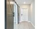 Hallway with gray accent barn door and ceramic tile flooring, leading to white front door at 1876 Colding Dr, Ruskin, FL 33570