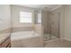 Bathroom featuring a tub, a glass enclosed shower, a window, and neutral tile at 20404 Autumn Fern Ave, Tampa, FL 33647