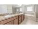 Bathroom featuring double sinks, a soaking tub, a glass enclosed shower, and tile flooring at 20404 Autumn Fern Ave, Tampa, FL 33647