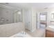 Bathroom featuring a tub, glass enclosed shower, neutral tile, and double sinks at 20404 Autumn Fern Ave, Tampa, FL 33647
